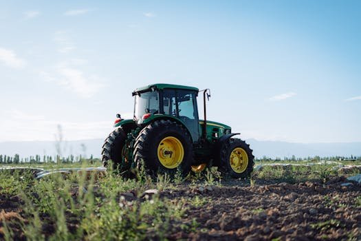 A vibrant tractor working in a sunlit farmland in Mendoza, Argentina.