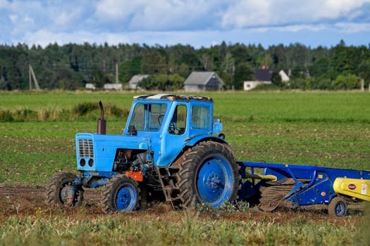 A classic blue tractor working in a lush green field in Harju County, Estonia.